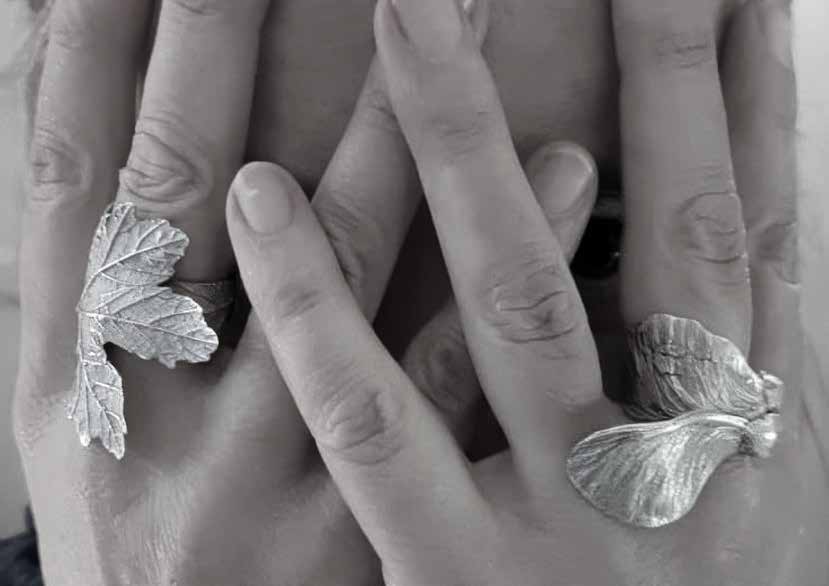 Hands wearing hand-cast silver leaf and ring jewellery by Sophie Grandval